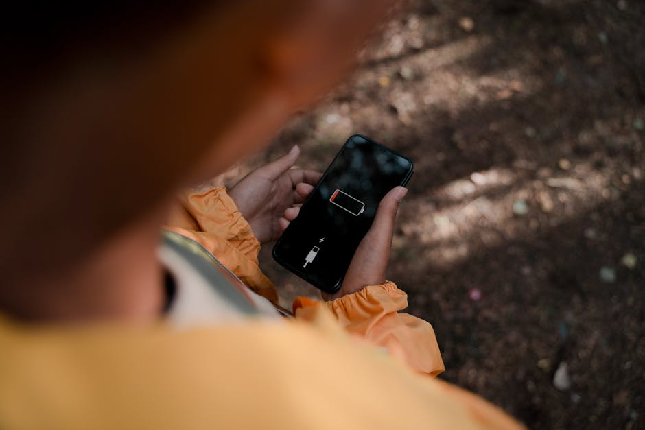 trzymany w rękach smartfon pokazujący wyczerpaną baterię