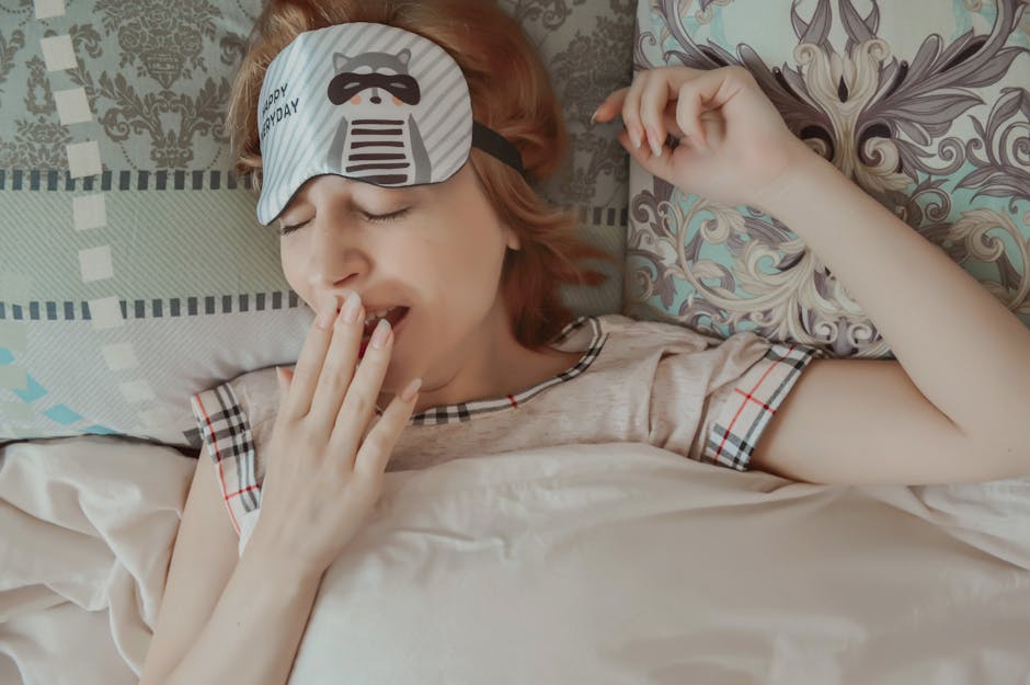 Kobieta w opasce na oczy z motywem szopa ziewa, leżąc w łóżku.