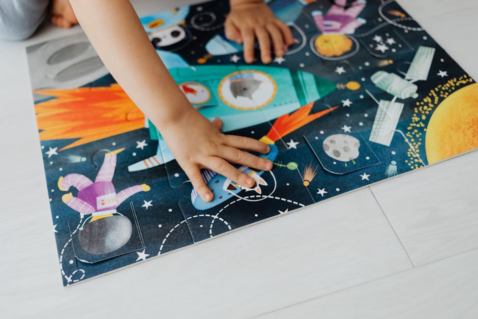 Dziecko układa kolorowe puzzle z motywem rakiety i kosmosu na podłodze.